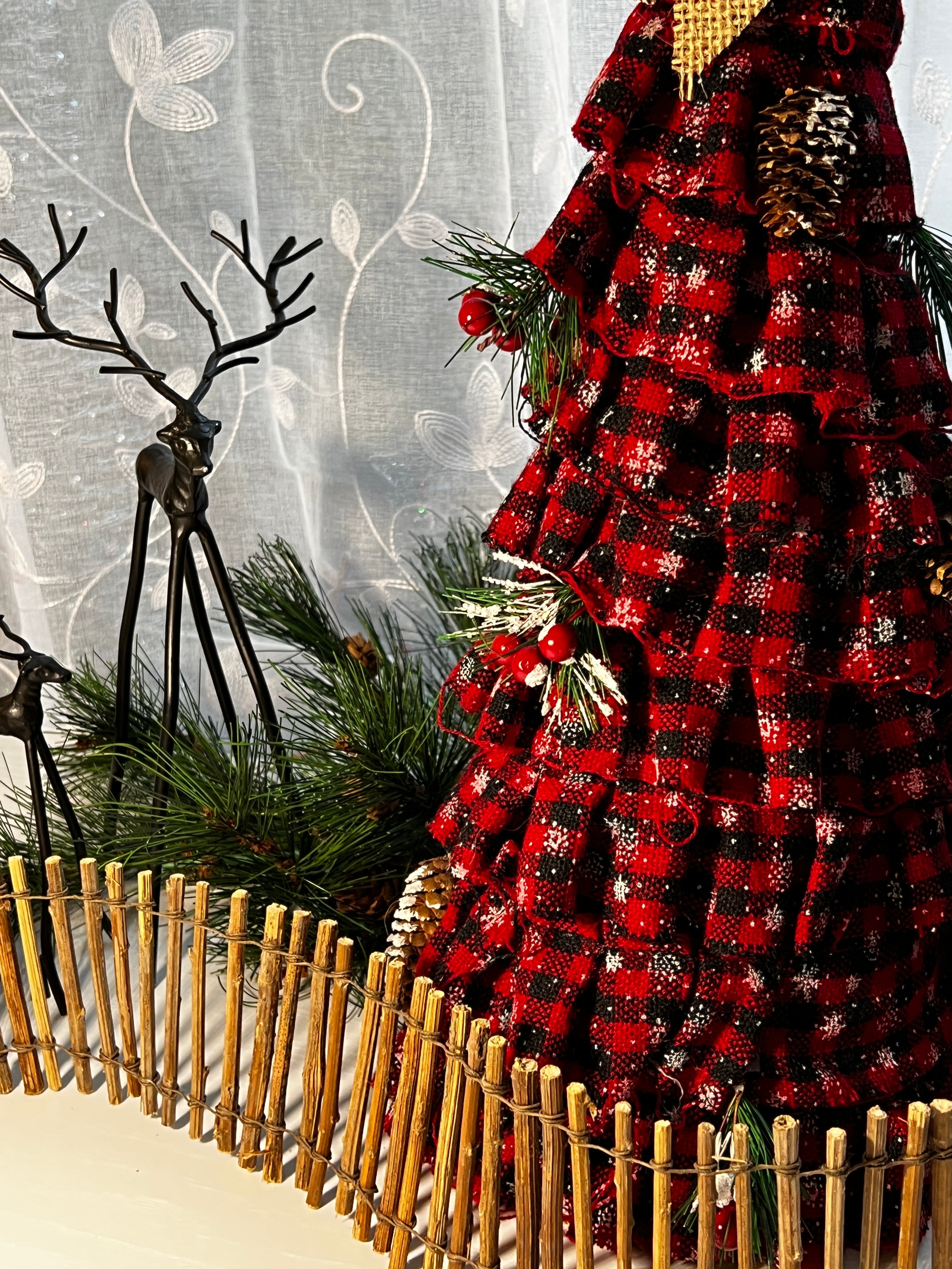 Red fabric christmas tree with metal reindeer and wooden fence